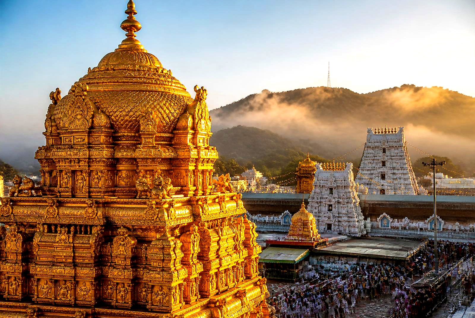 Golden vimana of Sri Venkateswara Temple at sunrise with mist over Tirumala hills