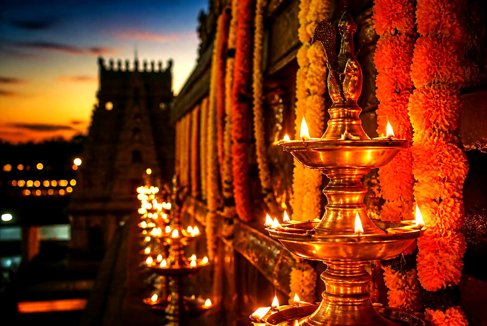 Brass oil lamps and marigold garlands glowing at the temple at dusk